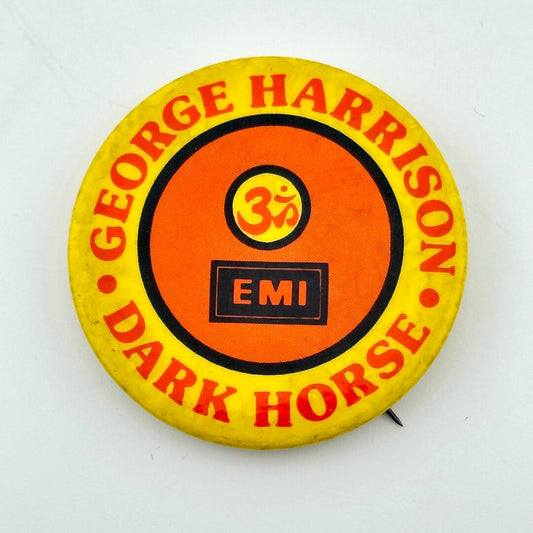 Yellow and orange pin with text, "GEORGE HARRISON, DARK HORSE." 