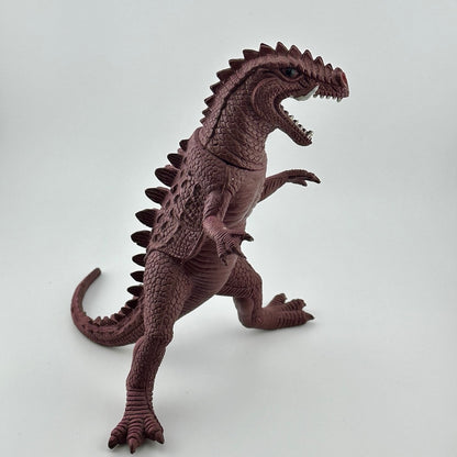 Side view of purple dinosaur type animal with white tusks & teeth, black eyes, long tail.
