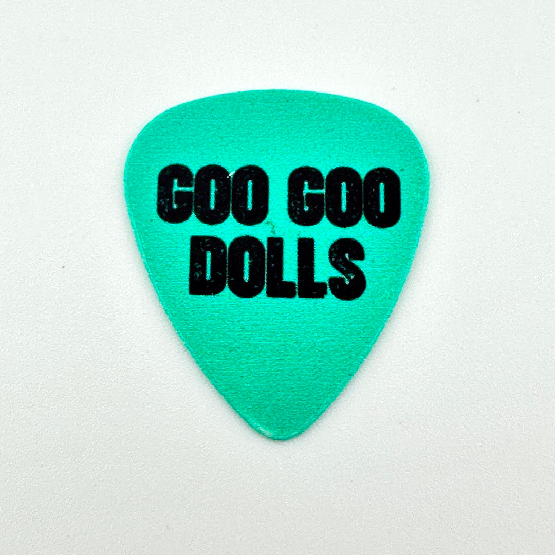 A turquoise blue guitar pick with the words 'GOO GOO DOLLS' printed in bold black letters, shown on a white background.