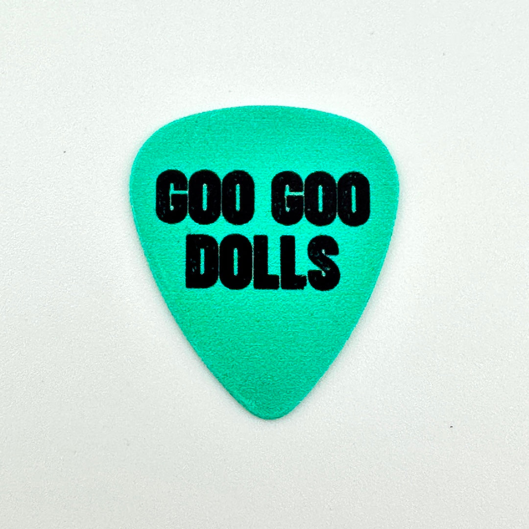 A turquoise blue guitar pick with the words 'GOO GOO DOLLS' printed in bold black letters, shown on a white background.