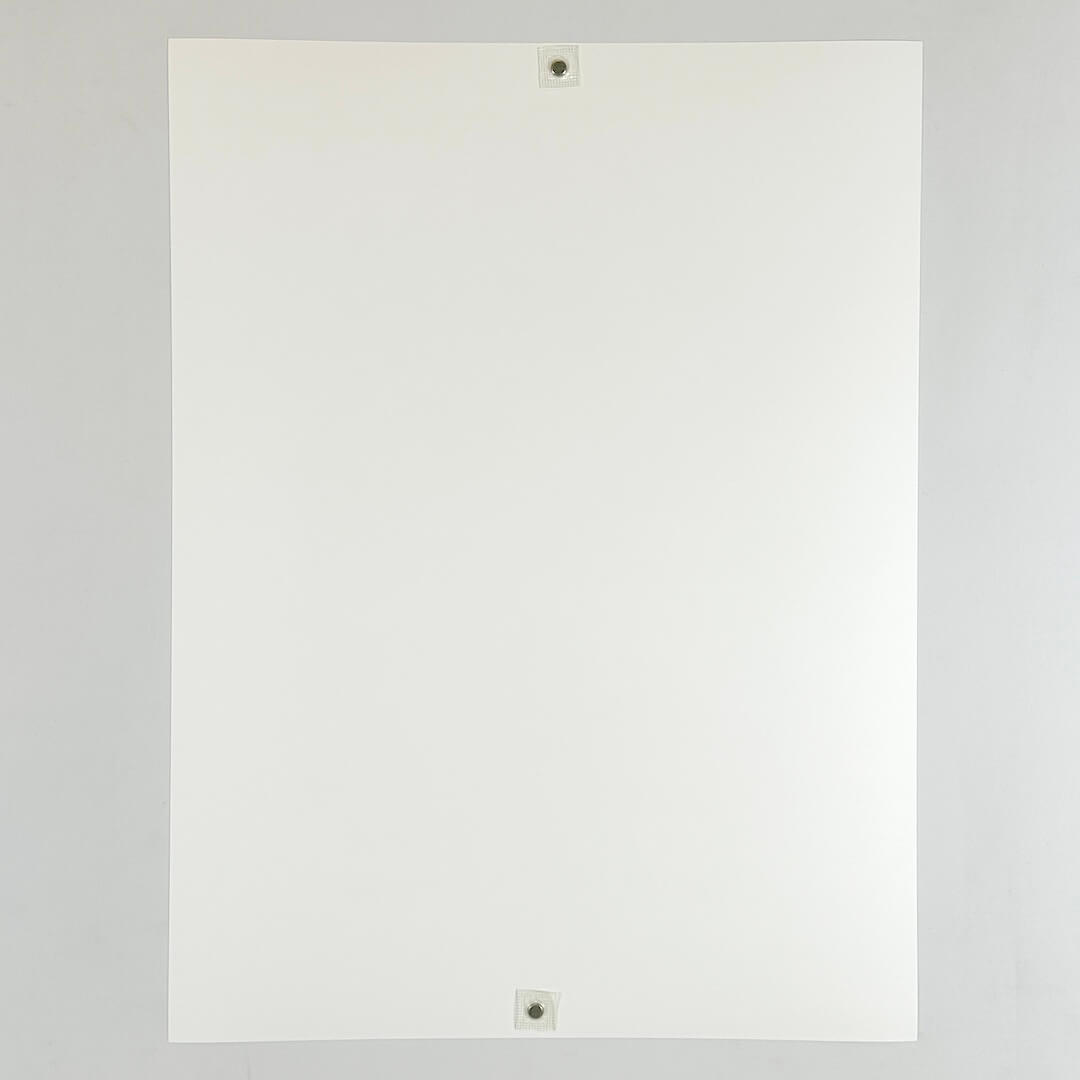Reverse side of print. A plain white sheet held up by two small magnets on a plain white background. 