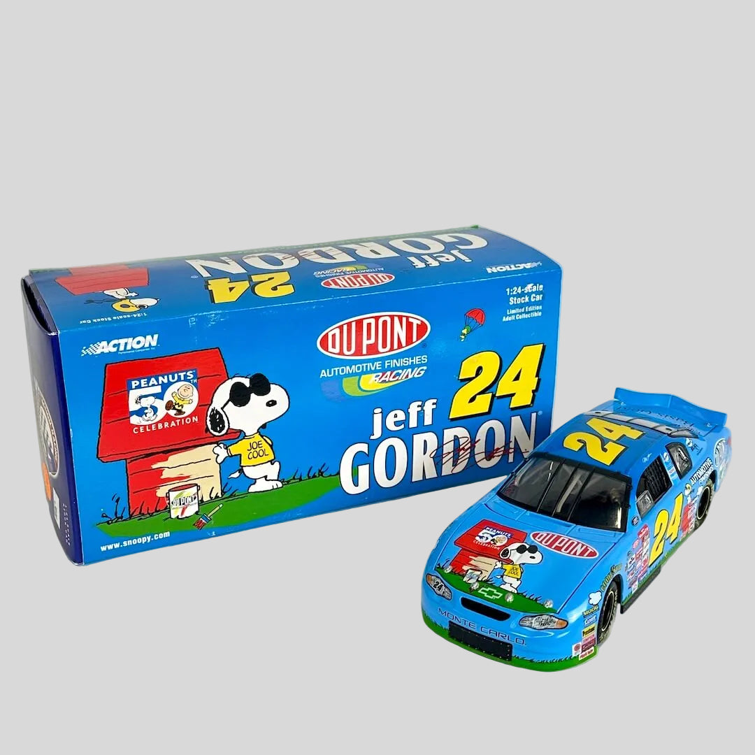 A blue diecast model race car next to its original packaging box. The box features Peanuts branding.