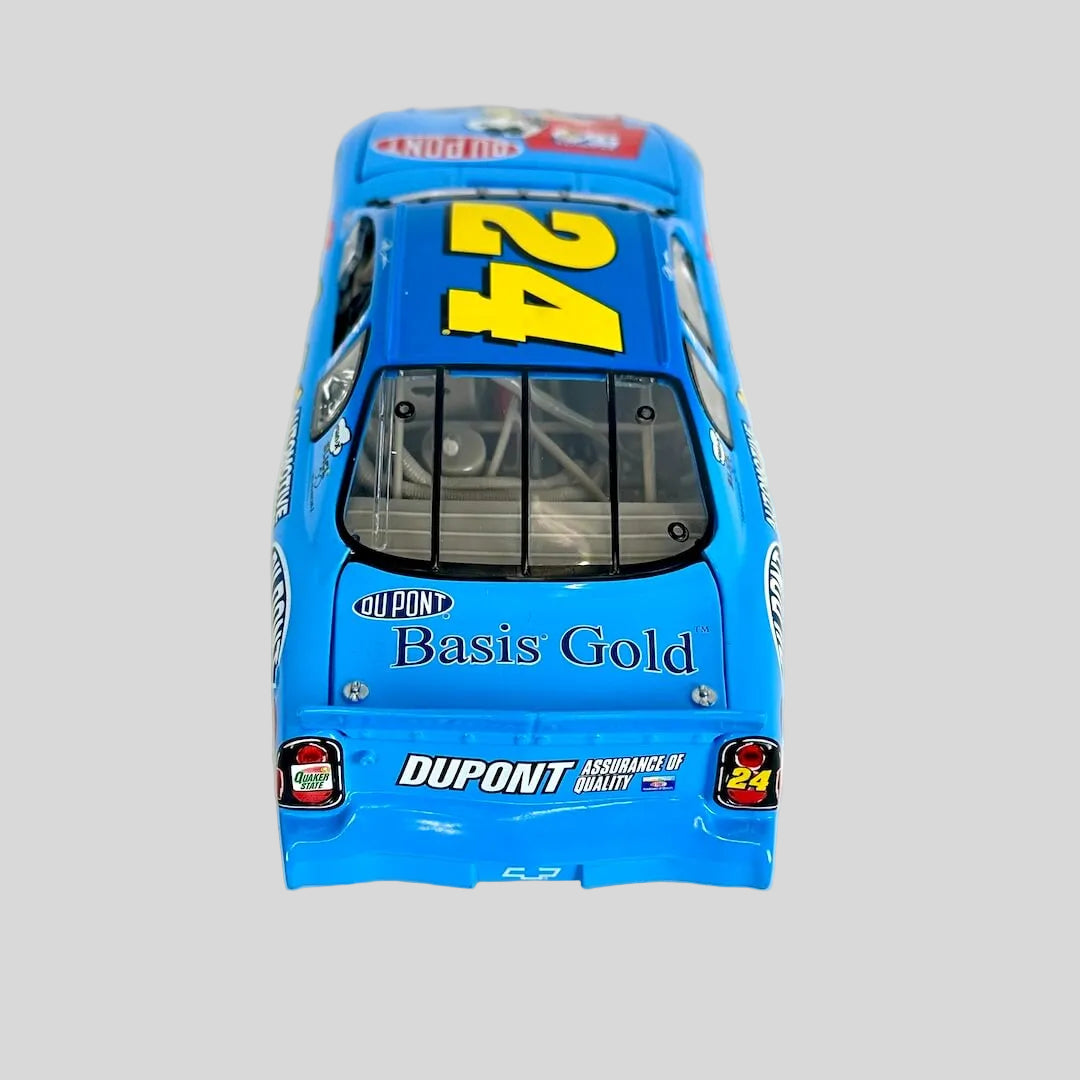 A blue diecast model race car viewed from the rear, featuring the number 24 in yellow on the roof, 'Basis Gold' on the trunk.