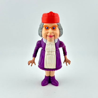 Toy figure of an elderly woman with a red hat and purple outfit on a light gray background