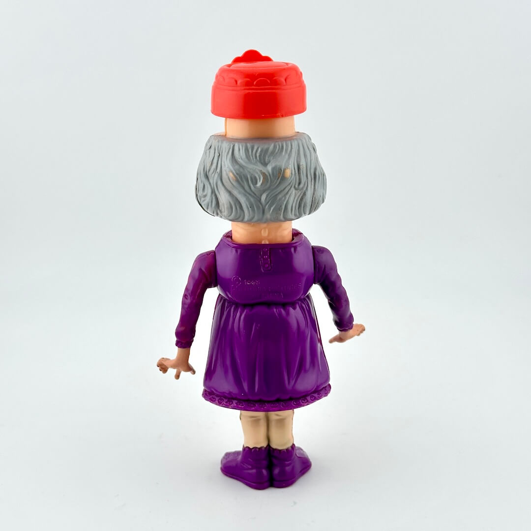 Toy figure of a character with a red hat and purple outfit on a white background