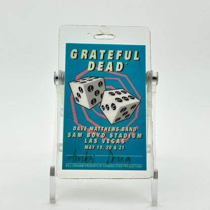 Laminated cyan blue backstage pass with pink swirl in back of two dice, white block text for event info.