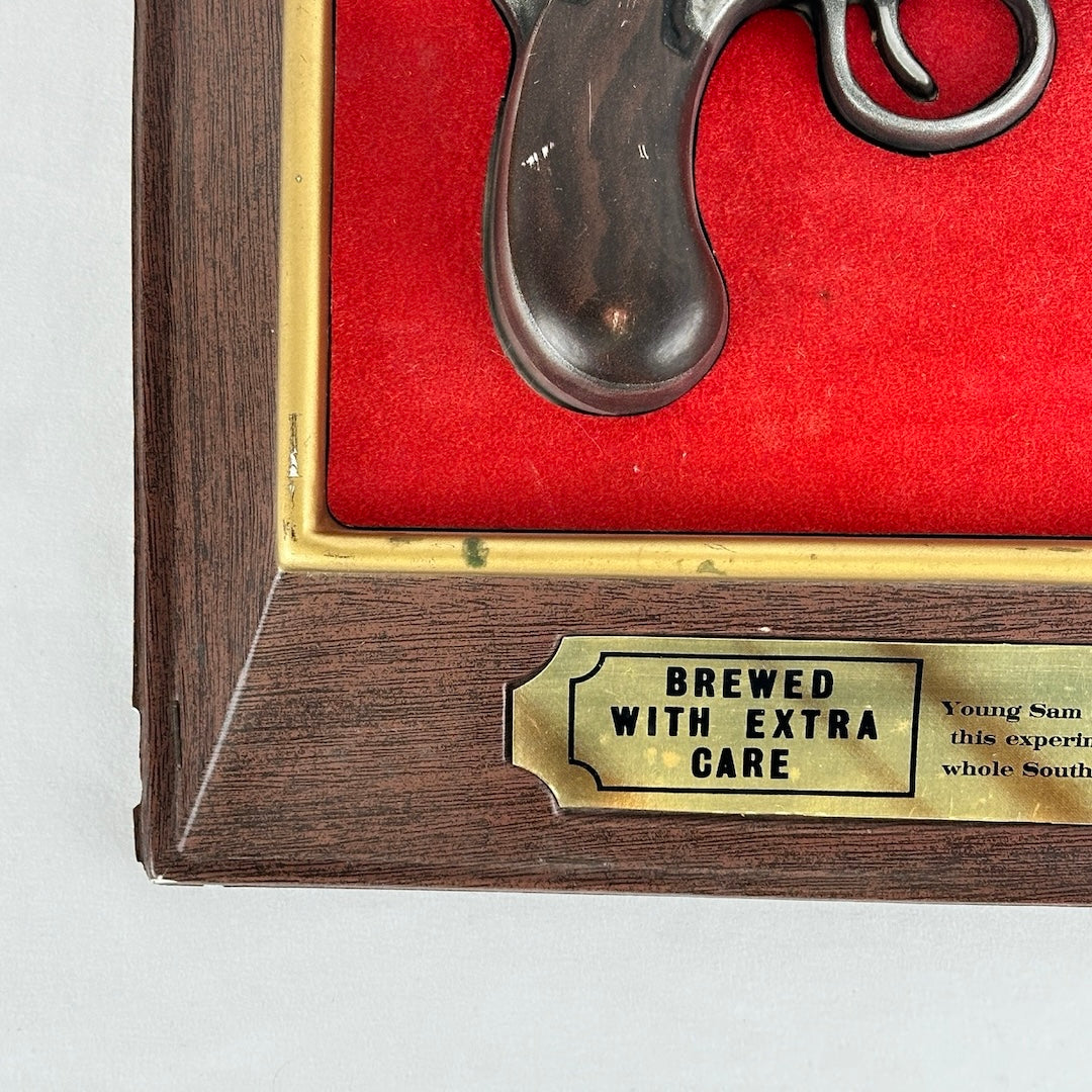 Close-up of a gold plaque at the bottom of the frame, engraved with the words: 'Brewed with Extra Care.' The plaque adds a refined touch to the vintage display."