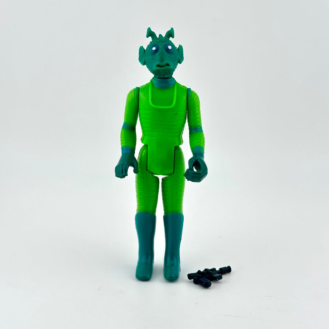 Green alien action figure with small black accessories on a white background