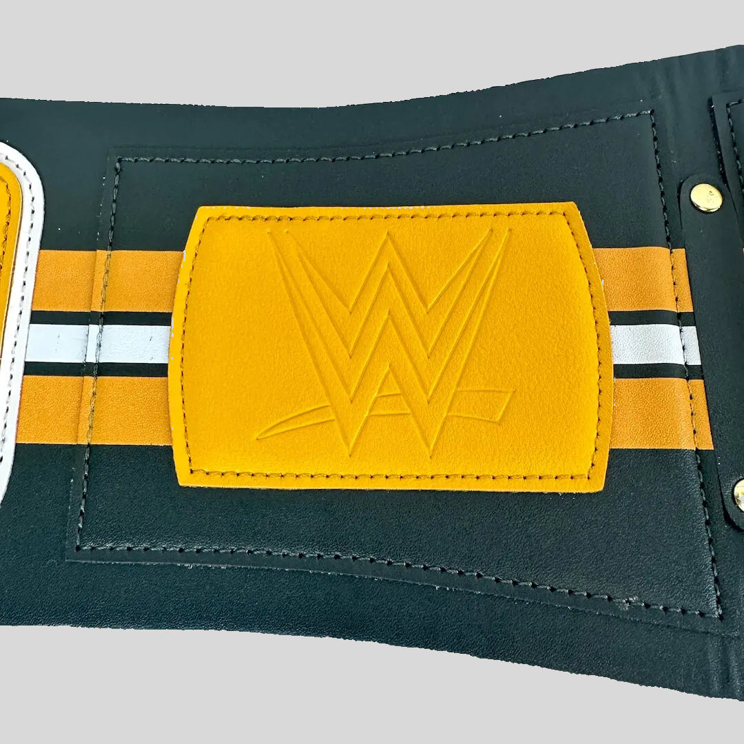 A close-up of a wrestling belt featuring a prominent yellow rectangular patch with an embossed WWE logo, flanked by yellow and white stripes.