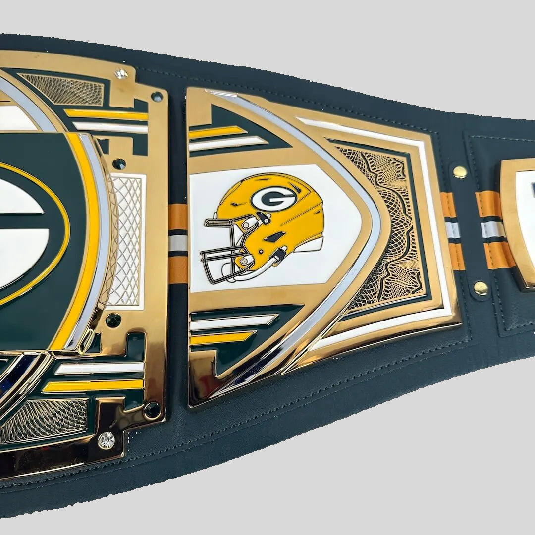 A close-up of a Green Bay Packers themed championship belt featuring gold and green metallic plates with the team logo and helmet design on a dark green leather strap.