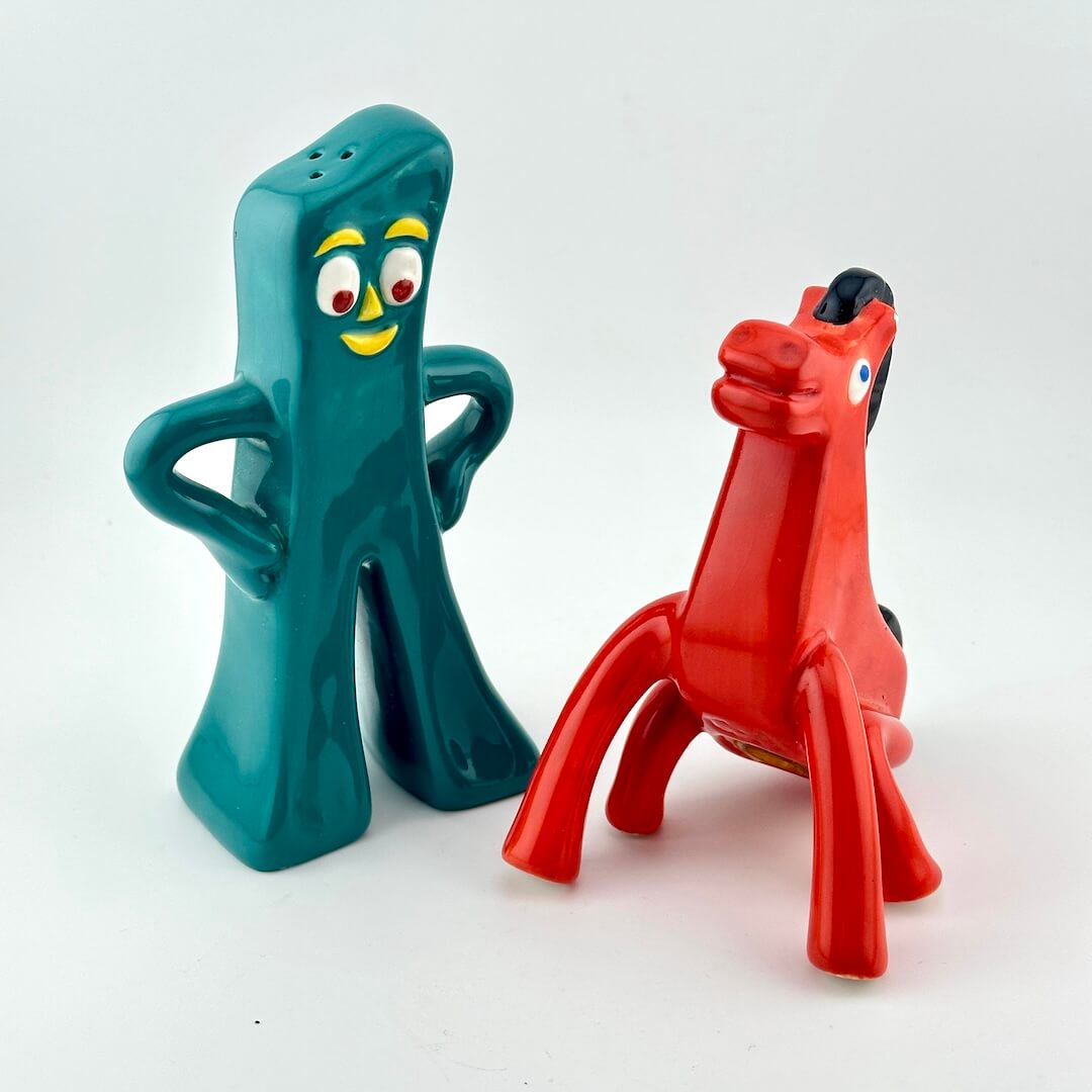 Two figurines: a tall teal figure with arms and legs and a red horse-like figure with a black mane.
