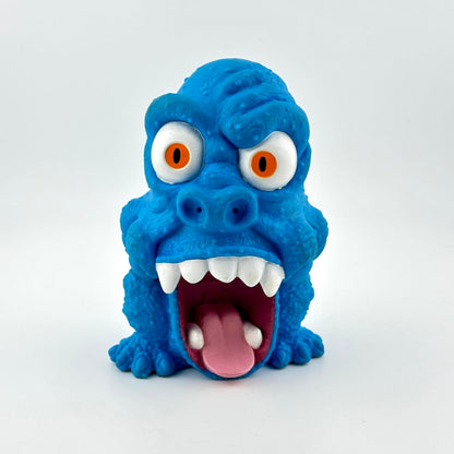 Blue monster toy with orange eyes and a wide open mouth on a white background