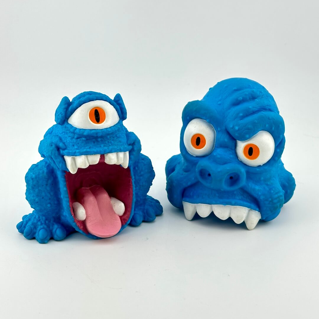 Two blue monster toys with open mouths on a white background