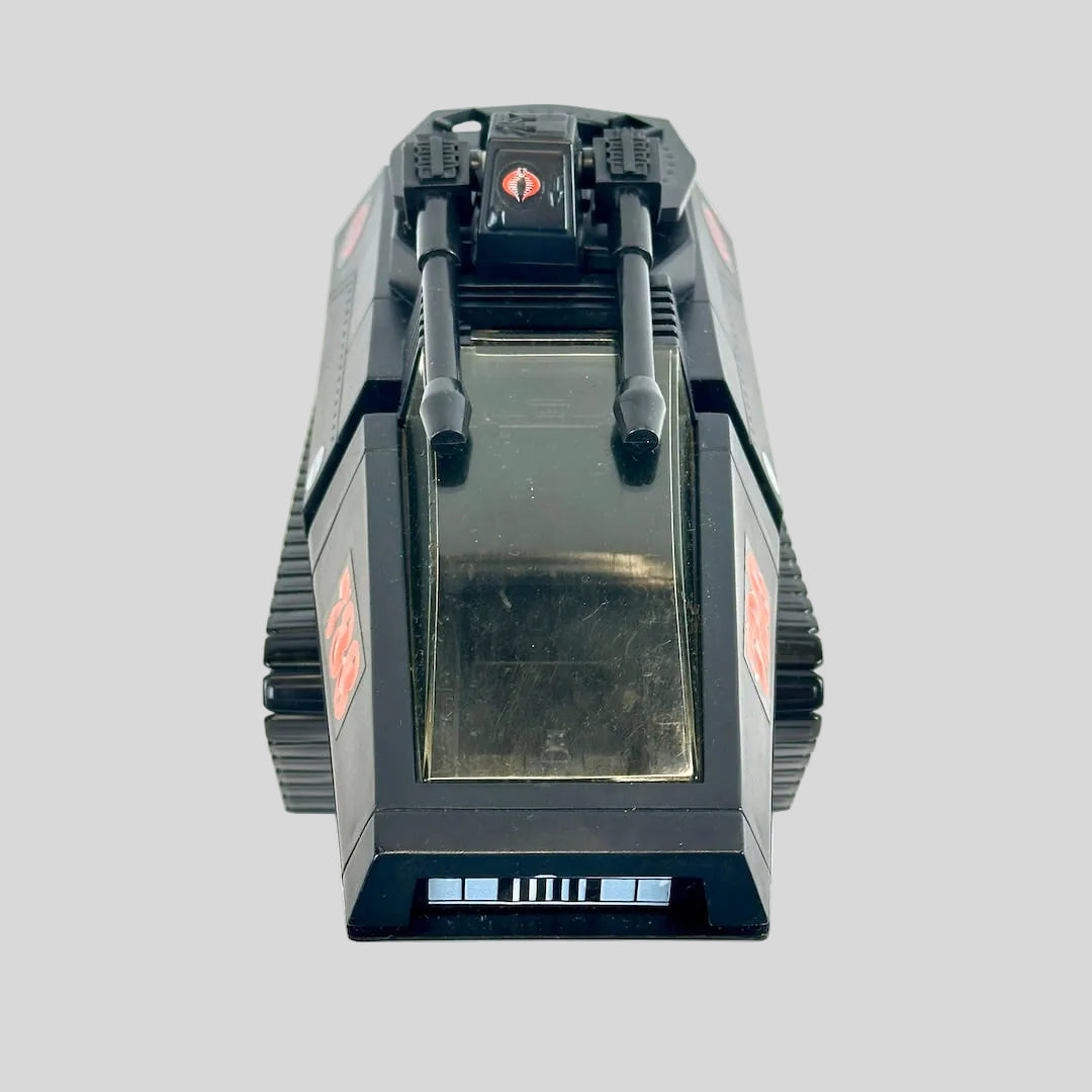 A vintage black toy tank or vehicle model photographed from the front on a light gray background.