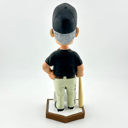 Bobblehead figure of a baseball player in a black cap and black shirt on a white background