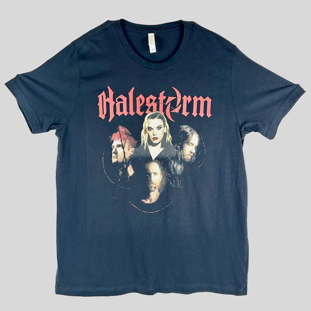 A black short-sleeve graphic t-shirt laid flat, 'Halestorm' in a red gothic font above a circular collage of band members' faces.
