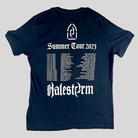 A black short-sleeve t-shirt laid flat, featuring a tour schedule and the text 'Summer Tour 2023' and 'Halestorm'.