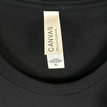 Close-up of a black Bella+Canvas crewneck shirt showing the neck label with size XL.