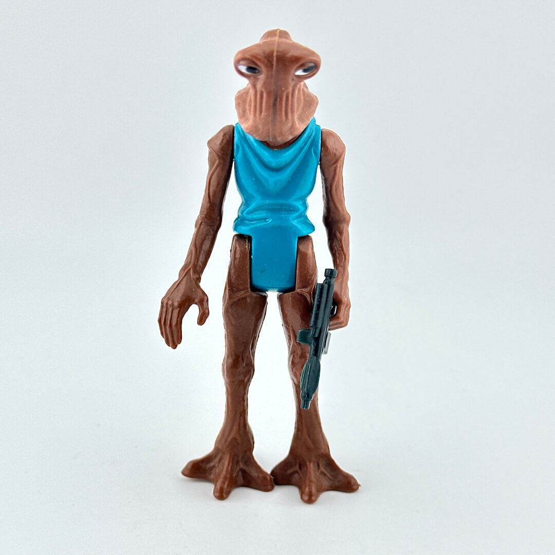 Toy figure of an alien with a blue tank top and gun on a white background