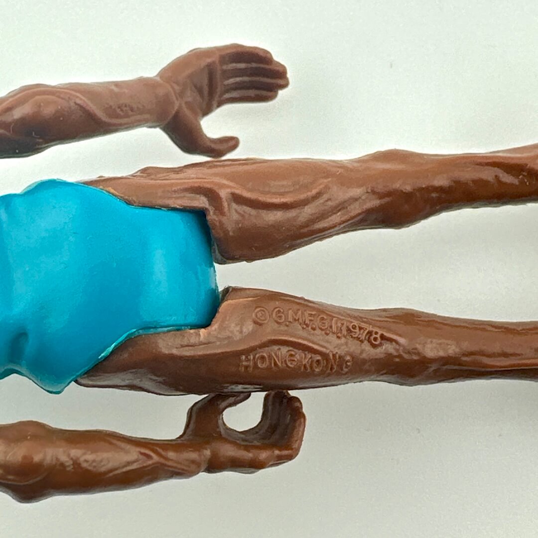 Toy figure with brown arms and legs holding a blue object on a white background