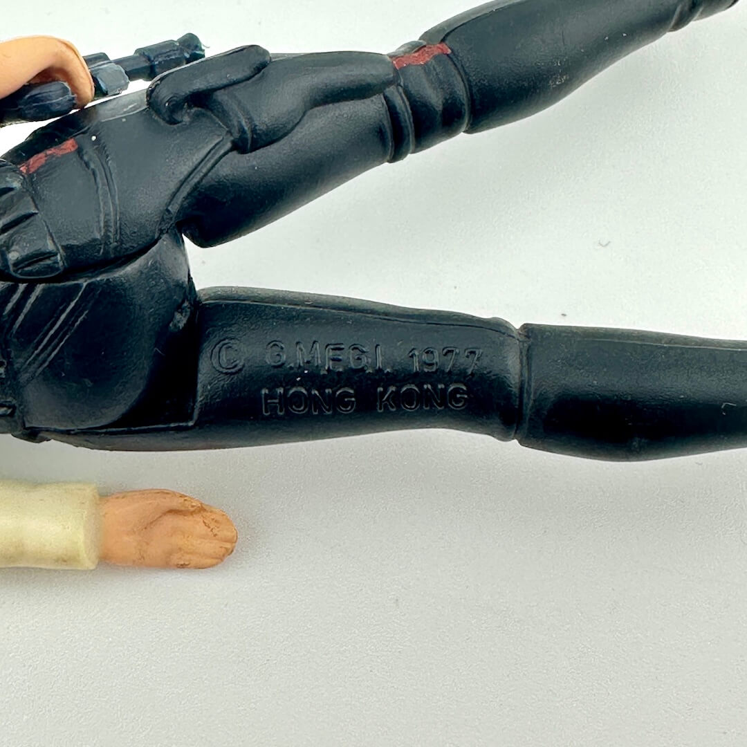 Black gun handle with 'OMELI 1977 HONG KONG' engraving on a white background