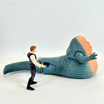 Toy figure of a character with a gun confronting a large, colorful creature on a white background