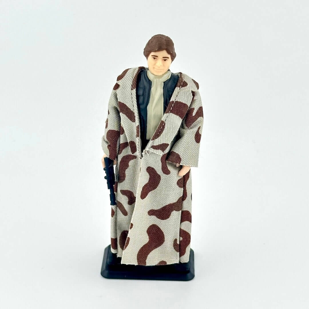 Action figure wearing a long coat with a camouflage pattern on a white background