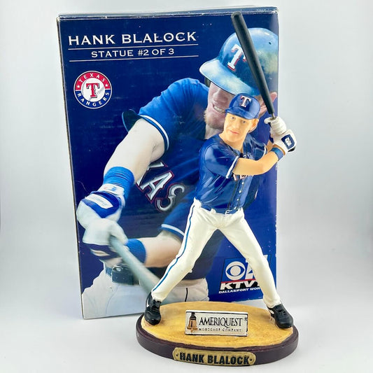 Baseball player figurine with bat in front of packaging displaying 'Hank Blalock' and Texas Rangers logo.