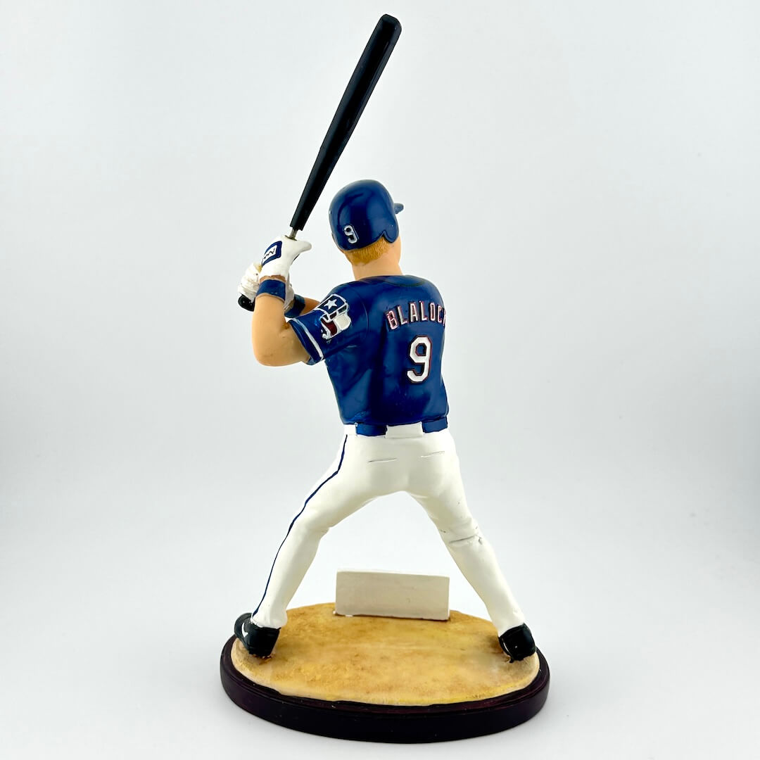 Baseball player figurine in a blue uniform with the number 9, holding a bat on a white background.