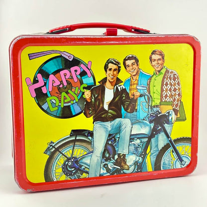 Happy Days lunchbox with yellow background and red border featuring illustration of the Fonz and other characters. 
