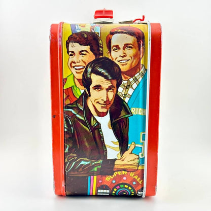 Side view of metal lunchbox with Happy Days characters illustrated in bright colors. 