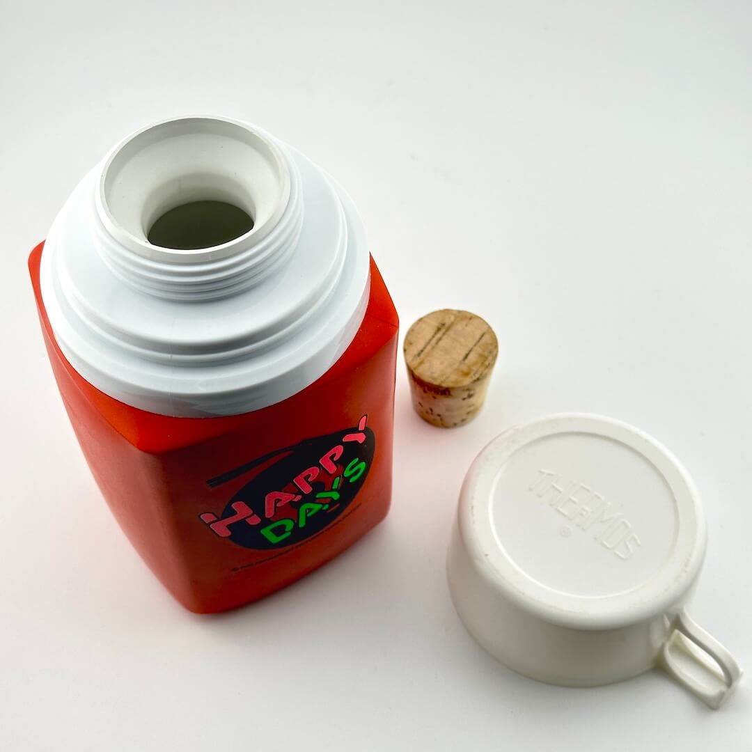 View of interior of thermos, with cork and cup lid. 
