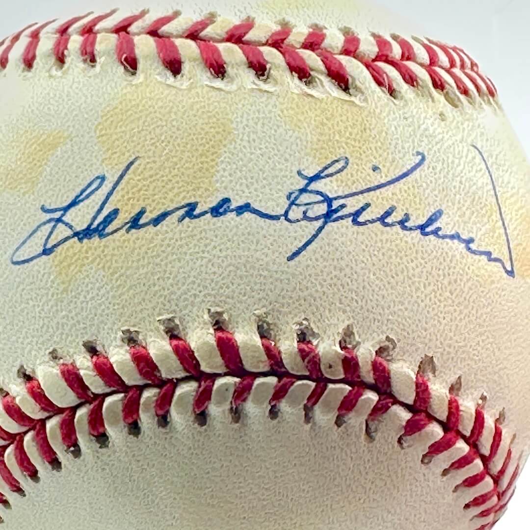 Close up of signed baseball in clear display against white background.