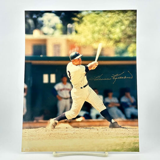 Baseball player in vintage uniform swinging a bat on a field with blurred background