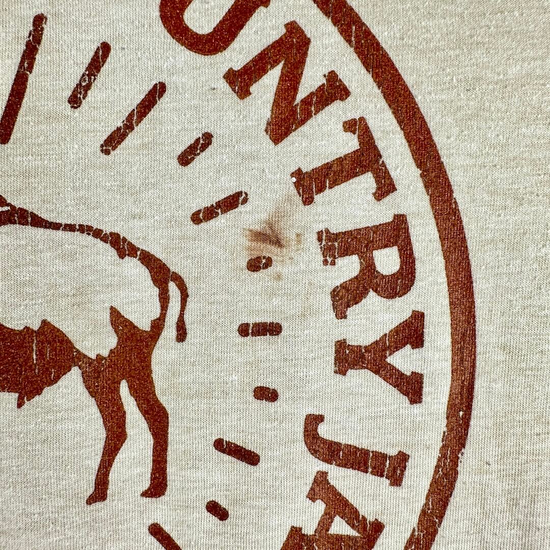 Close-up of a beige canvas-like fabric with a distressed brown stamped bull silhouette and partial text reading "JAYMA.