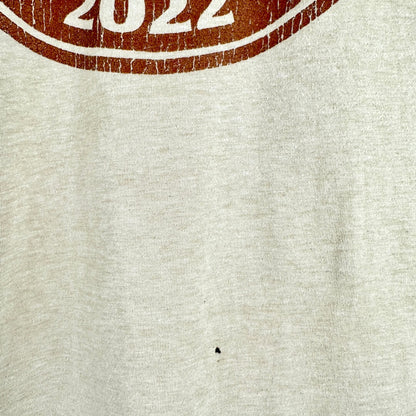 Close-up of a light heather gray fabric with a distressed brown circular graphic at the top edge showing the number 2.