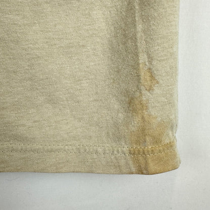 Close-up of a light beige or oatmeal-colored knit fabric corner with visible staining or discoloration near the hem.
