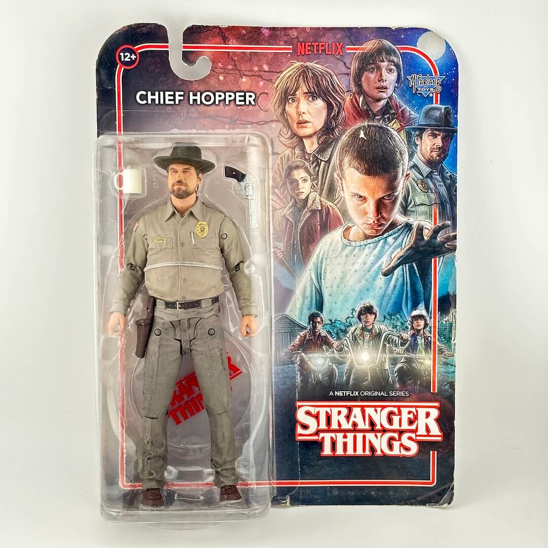 A packaged Stranger Things Chief Hopper action figure in front of its printed cardback. 