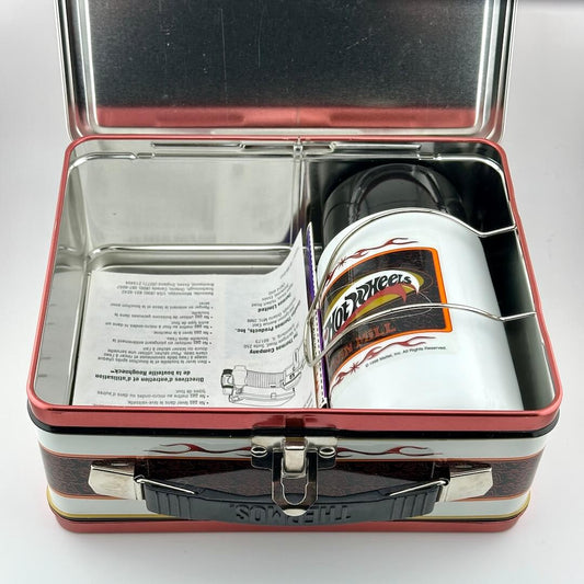 An open vintage-style metal lunchbox with a black handle, containing a white insulated canister with a Hot Wheels label.