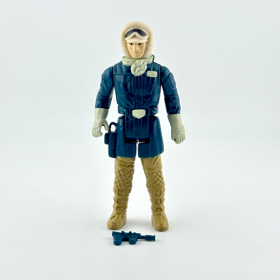 A vintage plastic action figure of a sci-fi character in a dark blue winter jacket, tan boots, and a beige hood.