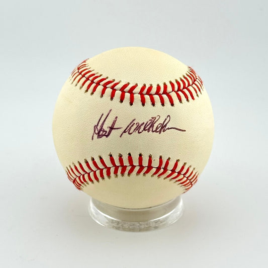 Baseball with red stitching on a clear stand against a white background
