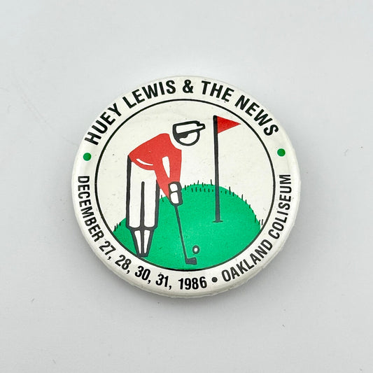 Circular button with "Huey Lewis & THe News" along top, with illustration of golfer in center, and event date along bottom. 
