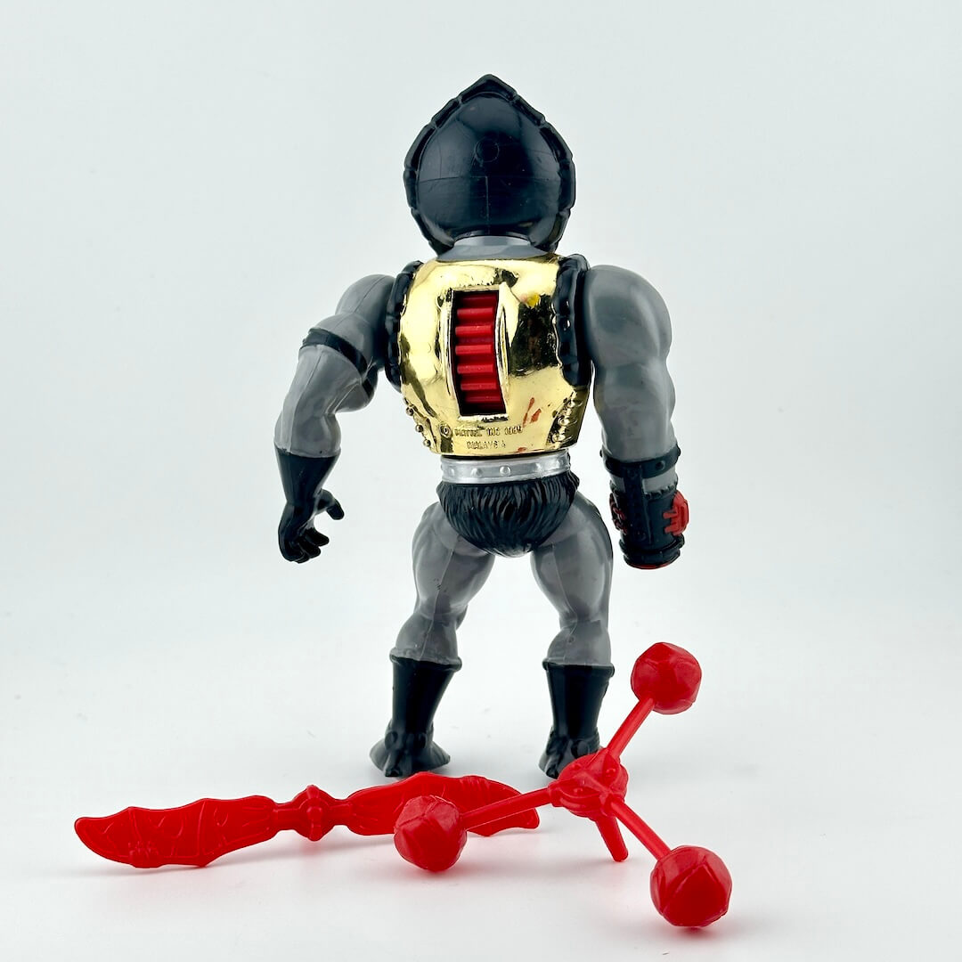 Toy figure with a red and gray outfit, gold chest armor, and two red accessories on a white background