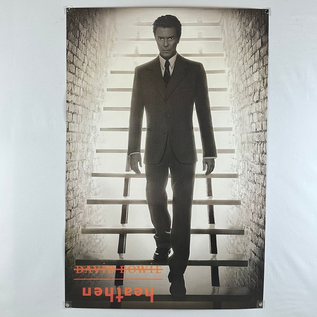 Poster of David Bowie walking down a set of stairs in a suite in black and white. 