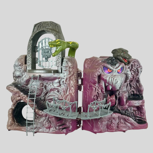 Purple/grey mountain with rock snake face by bridge spanning two sides of open playset, ladder descending from opposite side