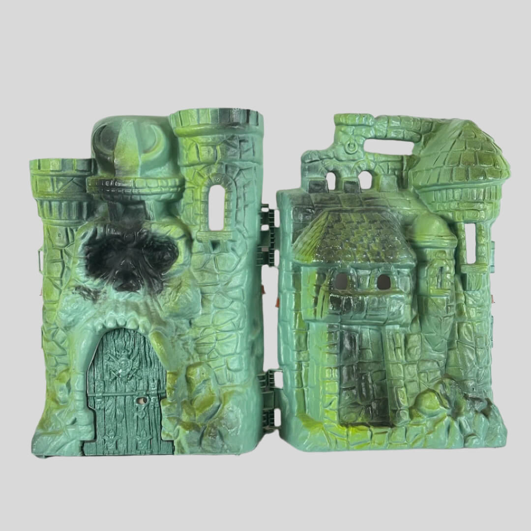 Varying green colored castle with skull face above main door, shield on door, and various openings for action figures. 