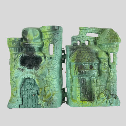Varying green colored castle with skull face above main door, shield on door, and various openings for action figures. 