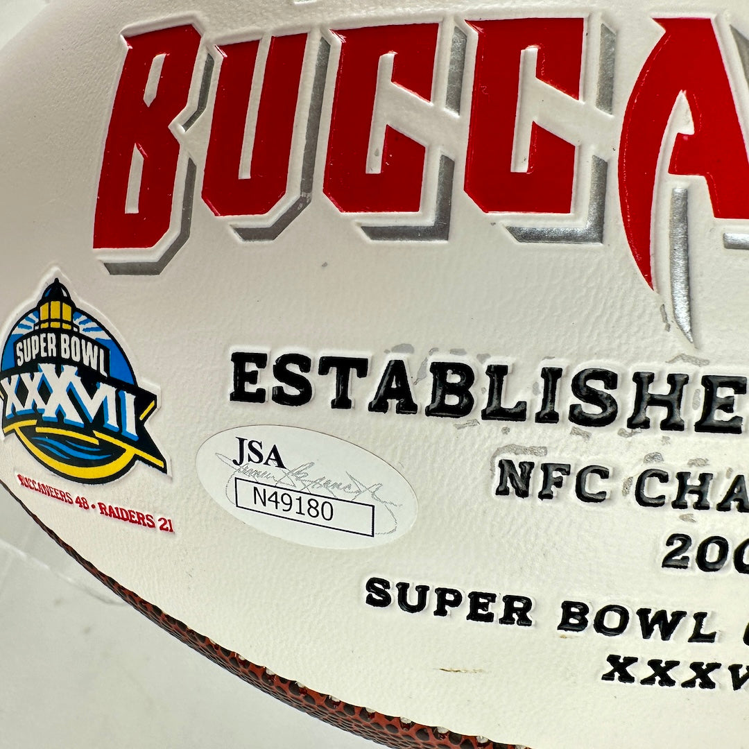 Close-up of a 'Buccaneers' sports memorabilia plaque with Super Bowl XXXVII logo and JSA certification.