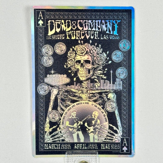 Promotional sticker for 'Dead & Company Forever' concert featuring a skeleton and musicians, on a rainbow foil background. 