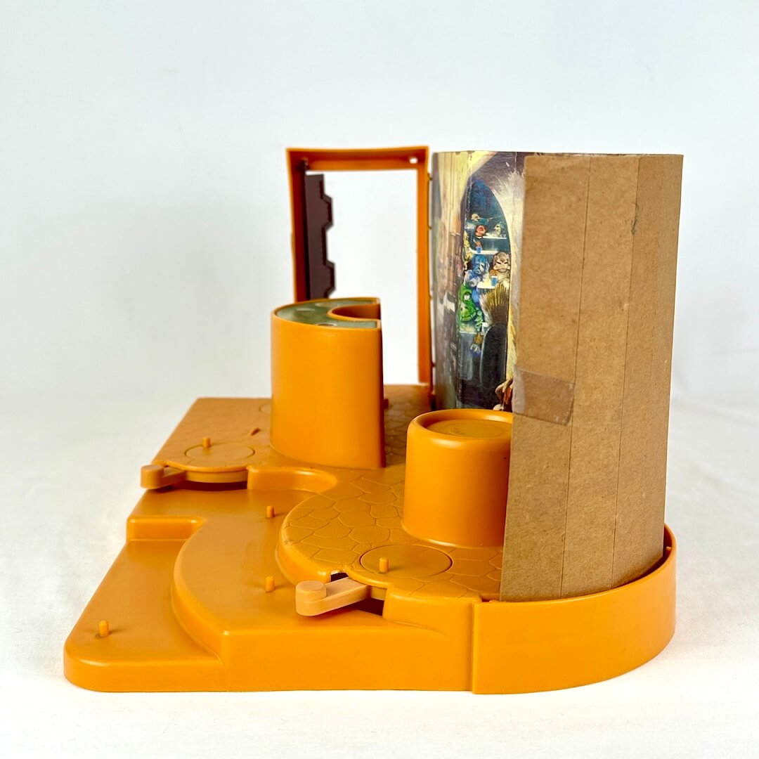 Other side view of Star Wars Cantina playset with orange base and background with colorful characters against white backdrop. 